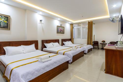 a hotel room with three beds and a television at Diamond Sea Hotel in Vung Tau