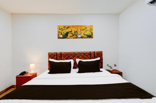 a bedroom with a large white bed with black pillows at Super Townhouse Vanasthalipuram Near Deer National Park in Hyderabad