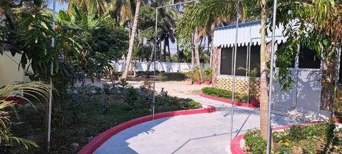 a garden with palm trees and a building and a sidewalk at Hotelswapnoneer in Diamond Harbour