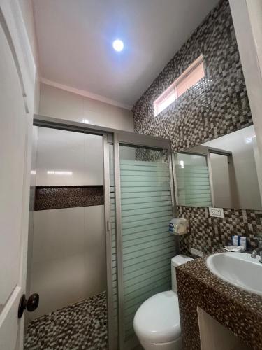 a bathroom with a shower and a toilet and a sink at Casa Greemat 5Habs AC piscina a pasos del mar in Zorritos