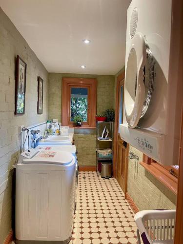 a kitchen with two sinks and a washing machine at Elsmere Heritage Gardens & Accom in Launceston