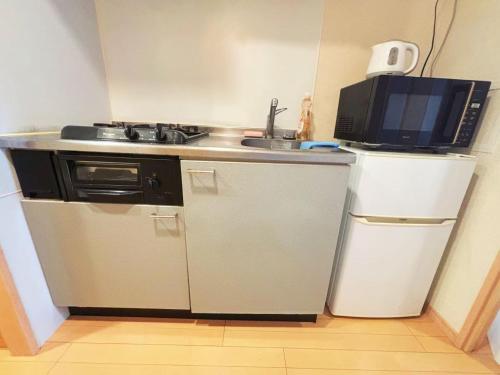 a small kitchen with a microwave and a refrigerator at ARSTAy池袋41 in Tokyo