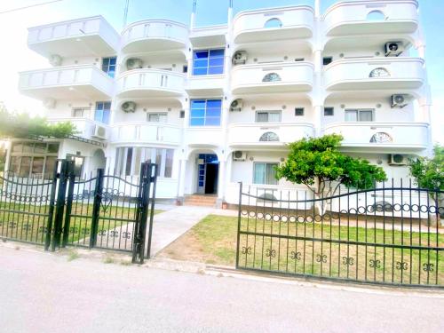 a white building with a fence in front of it at Apartments Hija in Donji Štoj