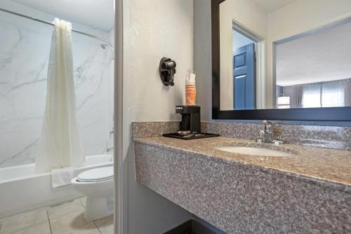 a bathroom with a sink and a toilet and a mirror at Quality Inn & Suites near Lake Eufaula in Eufaula