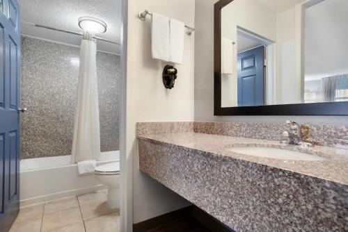a bathroom with a sink and a toilet and a mirror at Quality Inn & Suites near Lake Eufaula in Eufaula