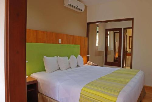 a bedroom with a large bed with a green headboard at Country Inn & Suites by Radisson, San Jose Aeropuerto, Costa Rica in San José