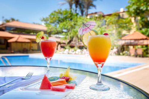 two drinks on a glass table next to a pool at Country Inn & Suites by Radisson, San Jose Aeropuerto, Costa Rica in San José