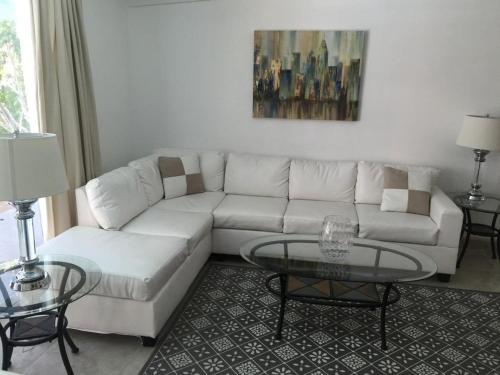 a living room with a white couch and two tables at Highland Gardens Hotel in Los Angeles