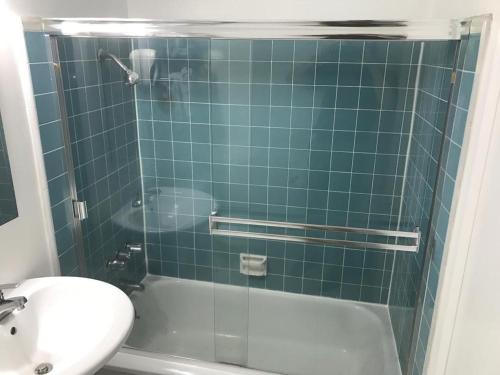 a green tiled bathroom with a tub and a sink at Highland Gardens Hotel in Los Angeles