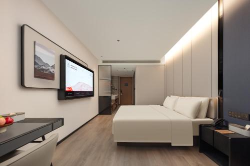 a living room with a white bed and a tv at Atour Hotel Hangzhou Xiaoshan Kaiyuan Plaza in Xiaoshan