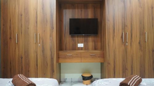 a bedroom with a tv in a wooden cabinet at Arcadia Homestay in Kāsarkod