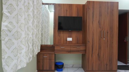 a wooden entertainment center with a television on it at Arcadia Homestay in Kāsarkod