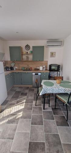 a kitchen with a table and chairs and a kitchen with green cabinets at Le petit Marius in Fayence