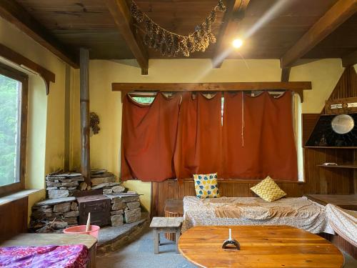 a living room with a red curtain and a table at Ananda grham in Kotla