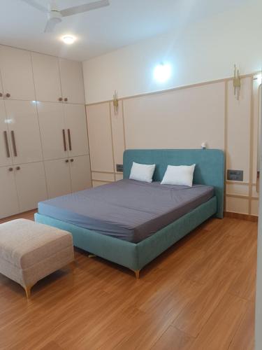a bedroom with a blue bed and a ottoman at Chandra in Bengaluru