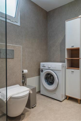 a bathroom with a washing machine and a toilet at Thea simply by the sea in Preveza