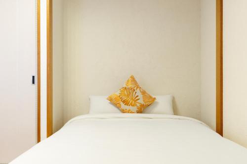 a bed with two pillows sitting on top of it at 駐車場2台 海中道路や伊計島にアクセス良好 和室付き 最大5名宿泊施設 Guest house mum in Uruma