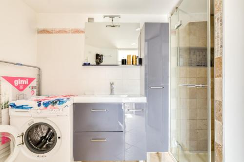 une salle de bain avec une machine à laver et un lavabo dans l'établissement Le Rayon de Soleil, à Martigues