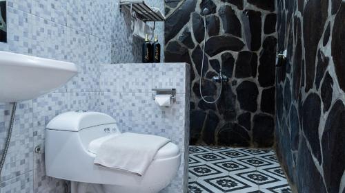 ein Badezimmer mit weißer Toilette und Waschbecken in der Unterkunft Padi Heritage Hotel in Karangjepun