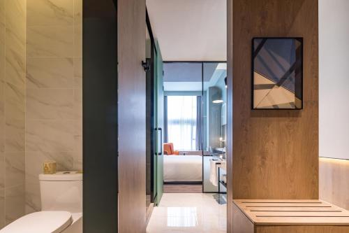 a bathroom with a toilet and a room with a bed at Atour S Hotel Shanghai Hongqiao Center Aegean-Late night Congee in Shanghai