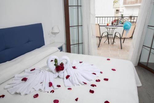Hostal Boutique Bajamar في نيرخا: سرير مع بجعة مصنوعة من الزهور