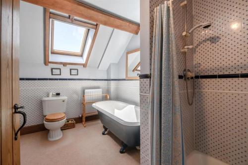 a bathroom with a tub and a toilet and a sink at Spacious 5 bed Barn in the Heart of Worcestershire in Lineholt