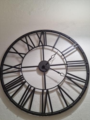 a black and white clock hanging on a wall at The Yellow House in Portimão