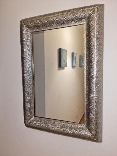 a mirror with a silver frame hanging on a wall at The Yellow House in Portimão