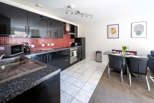 a kitchen with black cabinets and a table with chairs at Serviced Lettings 2 Bedrooms Central Location On site Parking in Norwich