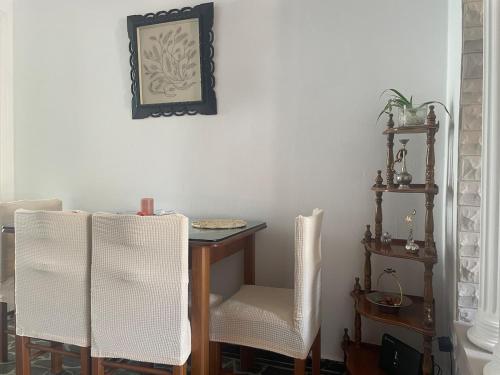 a dining room table with two white chairs and a table with at Enetiko Apartments in Chios