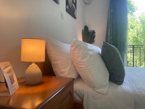 a bed with white pillows and a table with a lamp at Enetiko Apartments in Chios