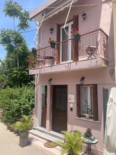 a pink house with a balcony and a door at Enetiko Apartments in Chios