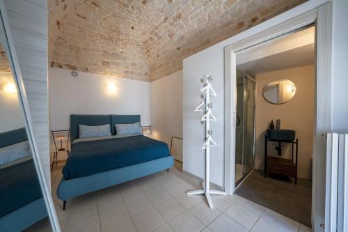 een slaapkamer met een blauw bed en een inloopdouche bij Aria di Ceglie authentic elegance in Ceglie Messapica