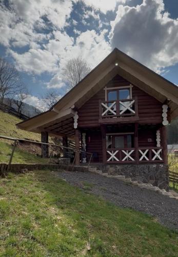 a log cabin with a fence in front of it at Котедж Під лісом in Synevyrsʼka Polyana