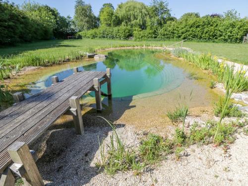 a wooden bench sitting next to a pond at Hazel in Witney