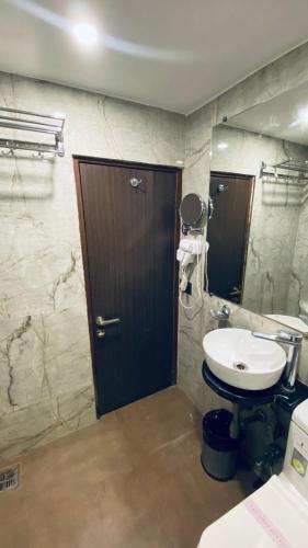 a bathroom with a sink and a wooden door at Gulf Hotel Mumbai- The Boutique Hotel Colaba Mumbai in Mumbai