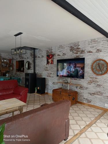- un salon avec un canapé et une télévision sur un mur en briques dans l'établissement Villa privée, piscine chauffée, jacuzzi et sauna, à Saint-André-dʼOlérargues