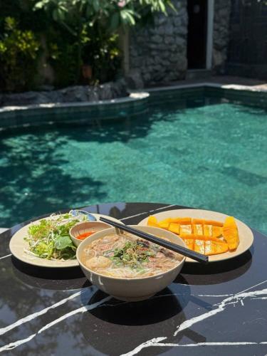 a bowl of food on a table next to a pool at IRIS HILL VILLA in Thôn Dương Xuân Hạ