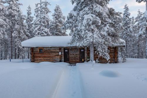 a log cabin in the snow with trees at Kuukkeli Log Houses Porakka Inn in Saariselka