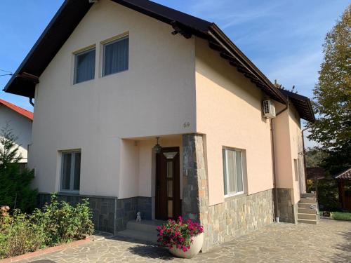 a white house with a door and some flowers at Casa cu Cires Breaza in Podu Vadului