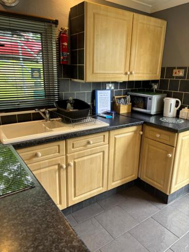 a kitchen with wooden cabinets and a sink at Glangwna Holiday Park in Caernarfon