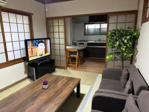 a living room with a couch and a tv at 和風庵Wafuna 7min walk to Teradacho Loop Line Station in Osaka