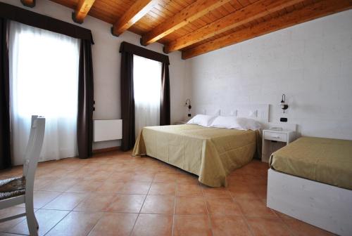 a bedroom with two beds and a window in it at Agriturismo Tenuta Kyrios con piscina in Borgagne
