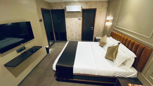 a bedroom with a large bed and a television at Gulf Hotel Mumbai- The Boutique Hotel Colaba Mumbai in Mumbai