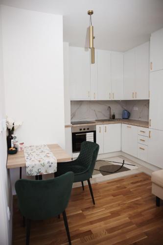 パレにあるApartman N Paleの白いキャビネットとテーブルと椅子のあるキッチン