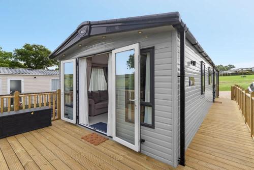 a grey tiny house on a deck at Rolling Hills Splash Escape - Fishing Nearby & Communal Swimming Pool ,Shut for the winter open April 2026 in Cheriton Bishop