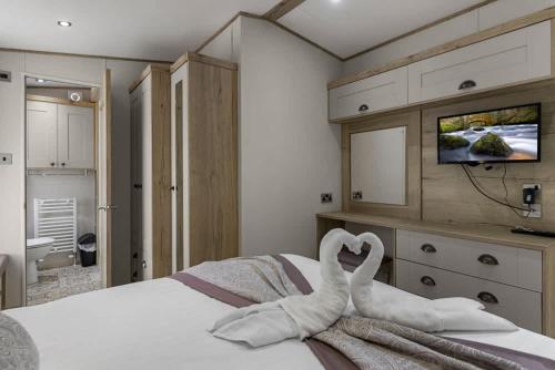 two swans sitting on a bed in a bedroom at Rolling Hills Splash Escape - Fishing Nearby & Communal Swimming Pool ,Shut for the winter open April 2026 in Cheriton Bishop
