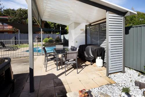 a patio with a table under a white pergola at Murrays Beach Studio Sawtell in Sawtell