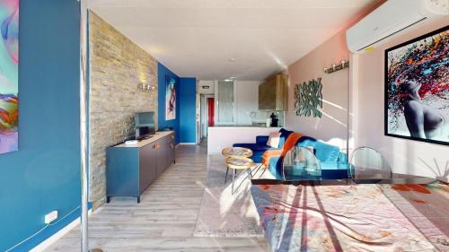 d'un salon avec une table en verre et des murs bleus. dans l'établissement Le Melrose Port Nature 5 Village Naturiste Cap d'Agde, au Cap d'Agde