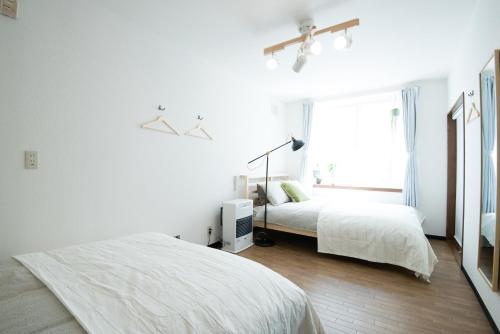 a white bedroom with two beds and a window at Grandeur South 9 in Minami-jūichijō